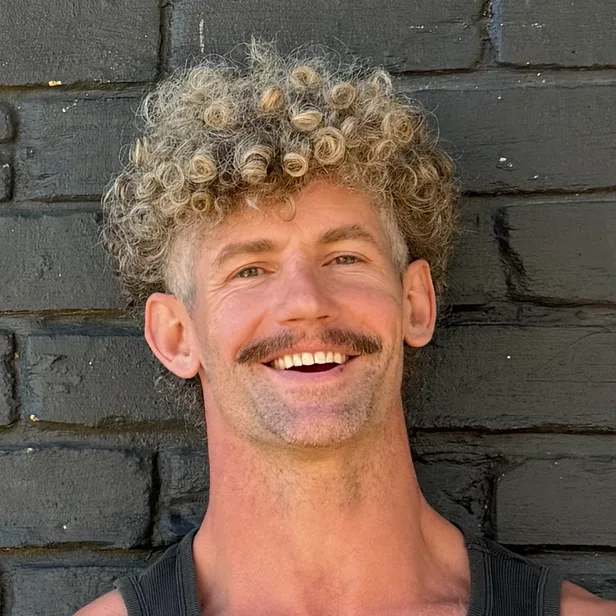 Brian Rippeto sonriendo frente a una pared de ladrillo negro